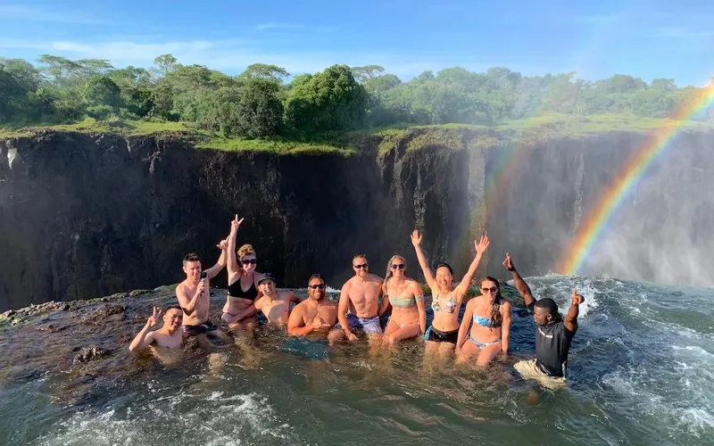 Swimmers standing at the edge of a waterfall above the drop